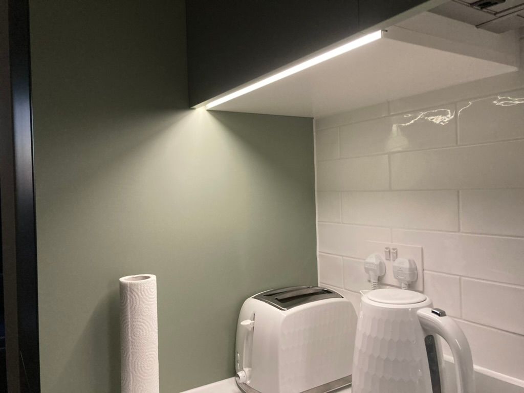 Kitchen corner showcasing LED under-cabinet lighting, kettle, and toaster.