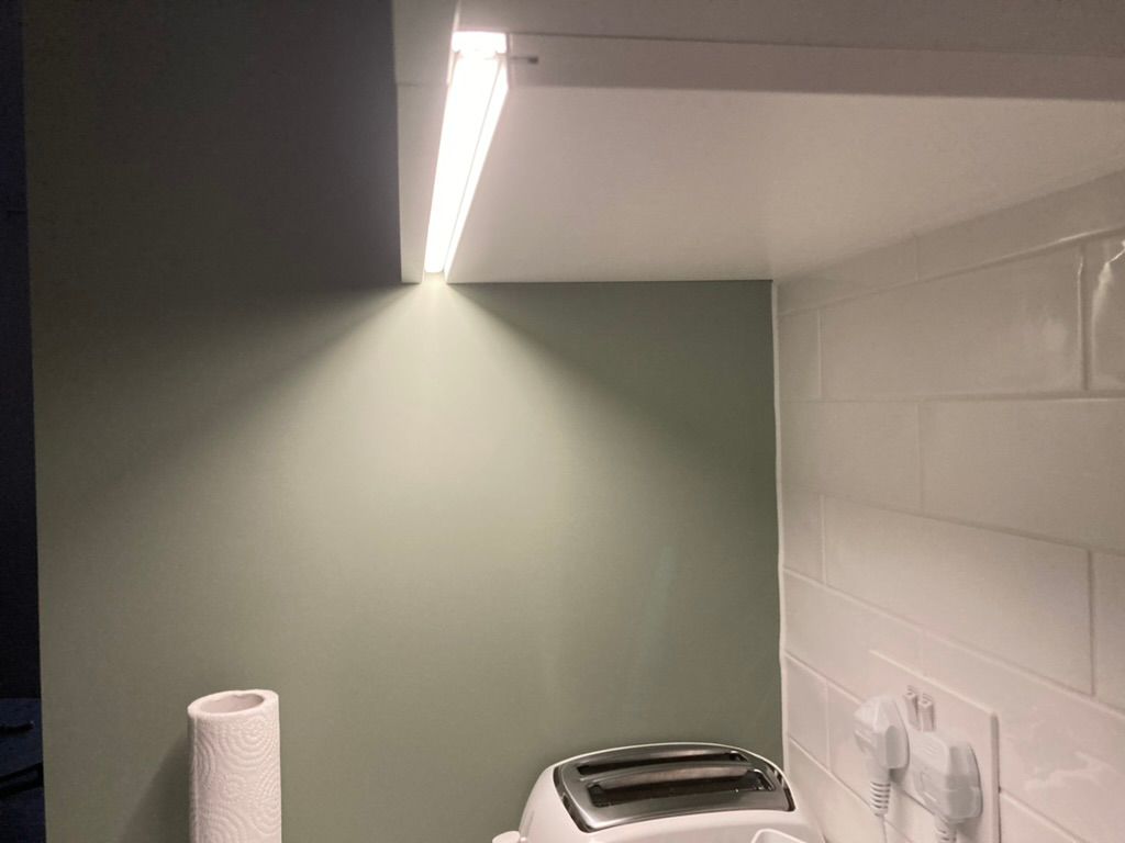 LED strip light mounted on a wall illuminates a kitchen corner.