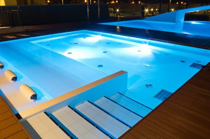 Illuminated swimming pool with blue LED lights and steps.