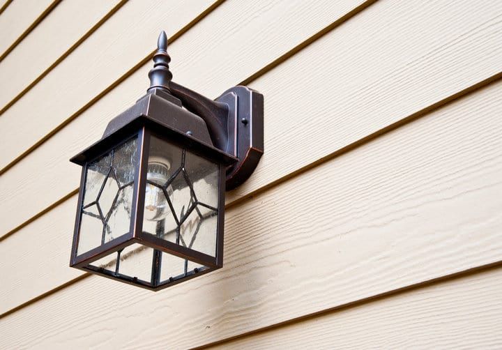 Wall-mounted lantern with a glass enclosure, showcasing visible light bulb inside.