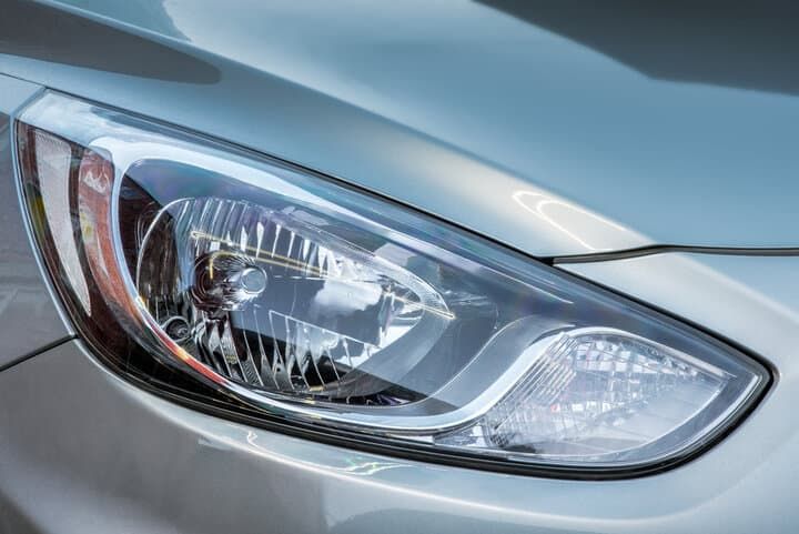 Close-up of a modern car headlight with clear glass lens and chrome accents.