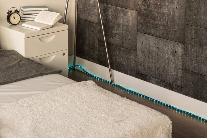 Cozy bedroom with LED strip lighting along the floor and textured wall.