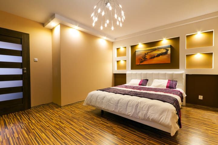 Modern bedroom featuring LED lighting and a stylish chandelier above the bed.