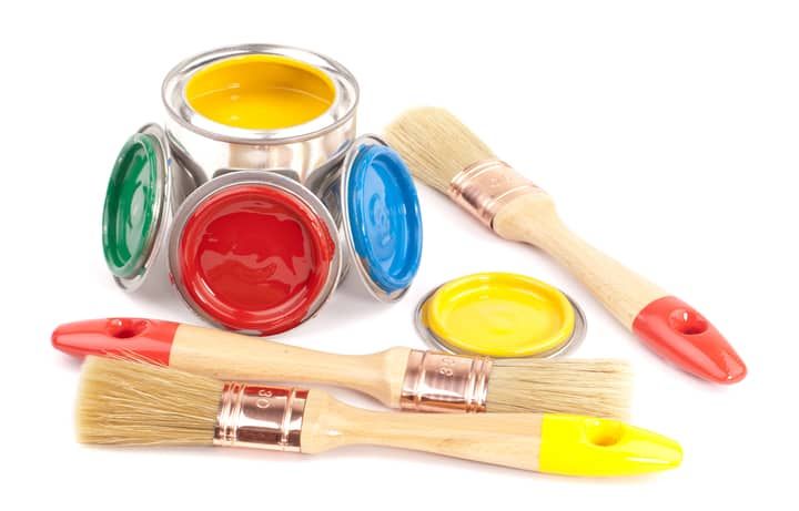 Four paintbrushes and cans of red, blue, green, and yellow paint.