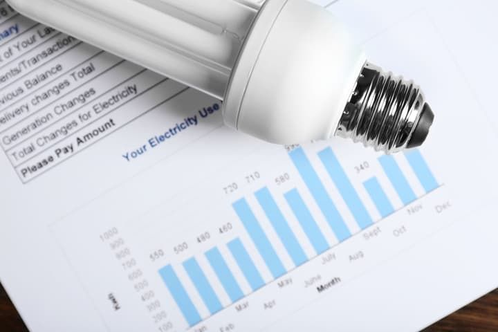 A compact fluorescent bulb on an electricity usage report with a bar graph.