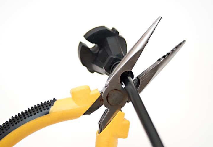 Close-up of pliers holding a black electrical wire with a socket.