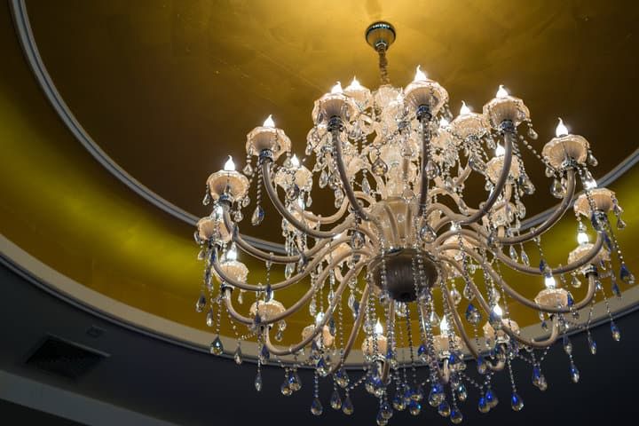 A lavish chandelier with ornate crystals illuminating a golden ceiling.