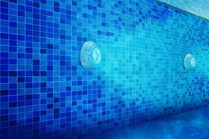 LED lights illuminate a blue tiled pool wall under clear water.
