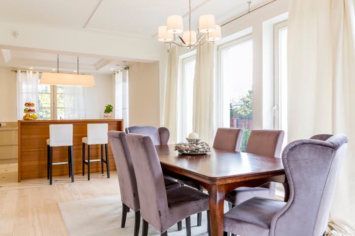 Brightly lit dining area with elegant wooden table and plush chairs.