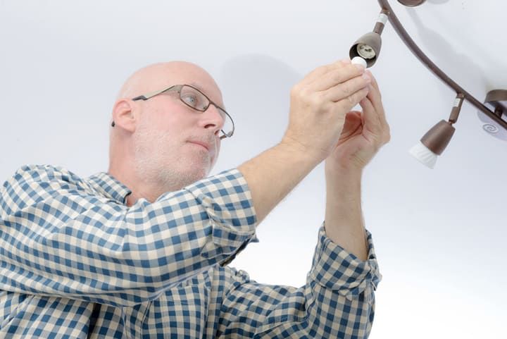 A person changing a light bulb on a ceiling fixture.