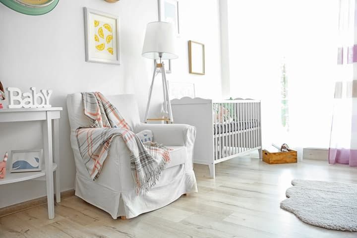 Cozy nursery featuring a white armchair, stylish lamp, and crib.