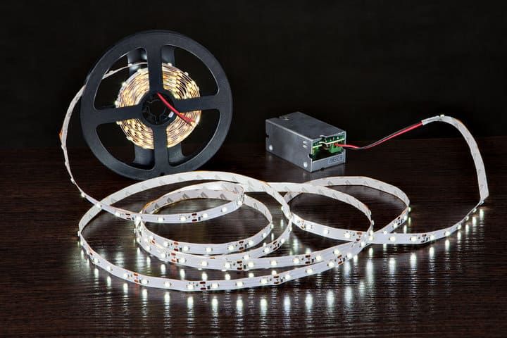A coil of LED light strips with a power supply on a dark surface.