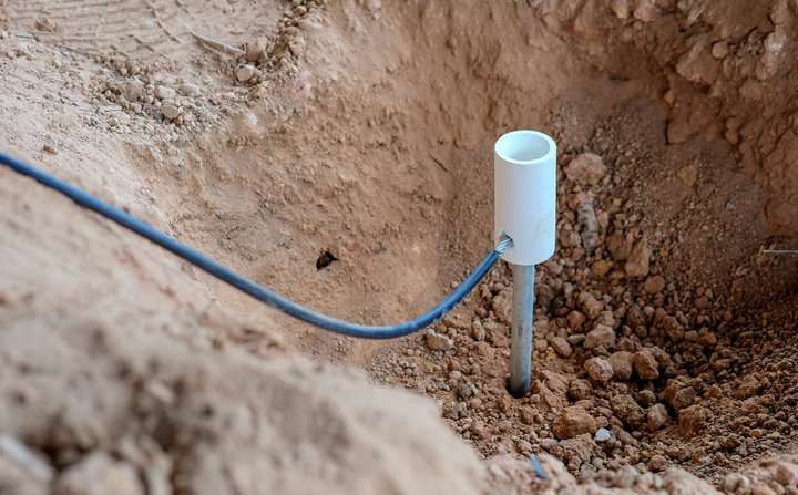 A buried pipe with a wire emerging from the soil in a construction site.
