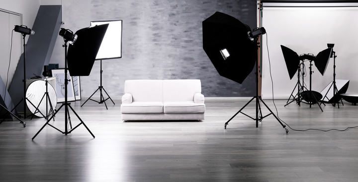 Brightly lit studio scene with a white couch and multiple light stands.