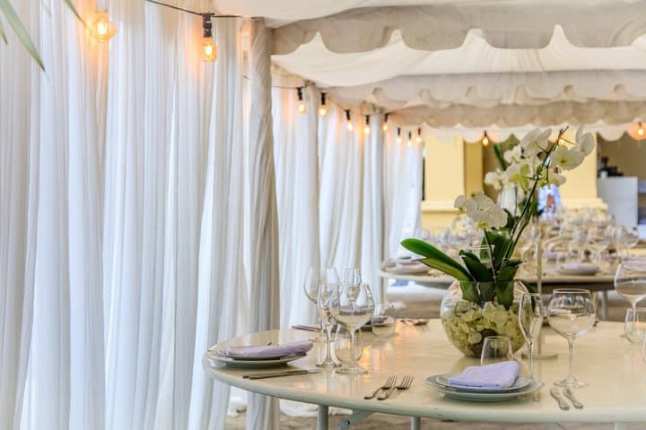 Elegant dining setup with white curtains and warm LED string lights.