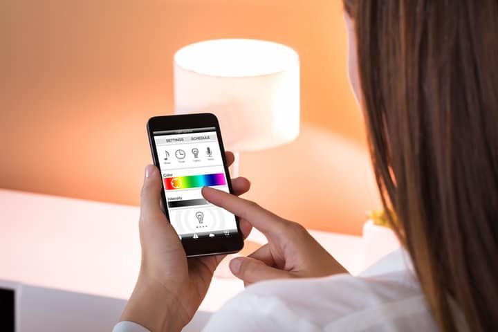 Person adjusting LED lights using a smartphone app with color controls.