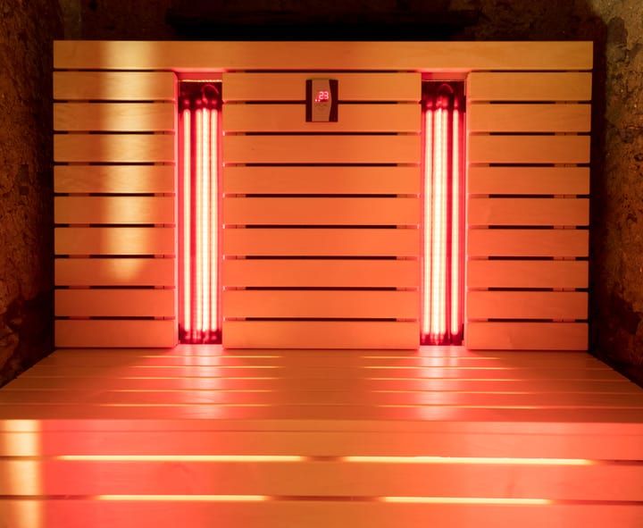 Wooden sauna interior with red LED lights glowing brightly.