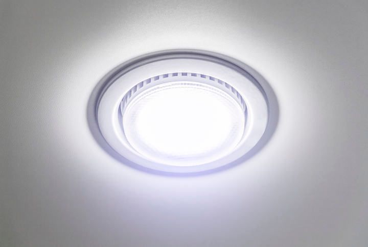 Bright round LED ceiling light fixture illuminating a white surface.