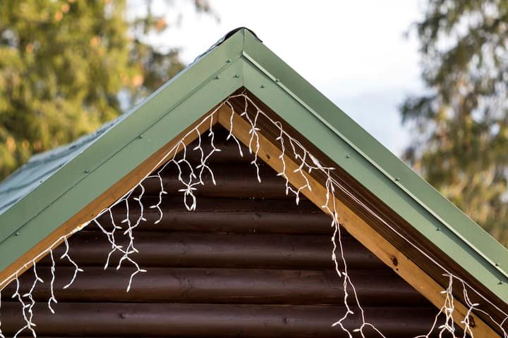 Green roof edge with white LED string lights hanging down.
