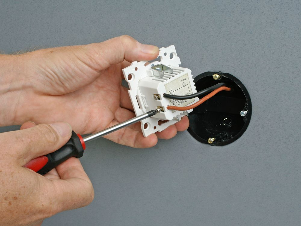 Person using a screwdriver to install an LED lighting fixture.