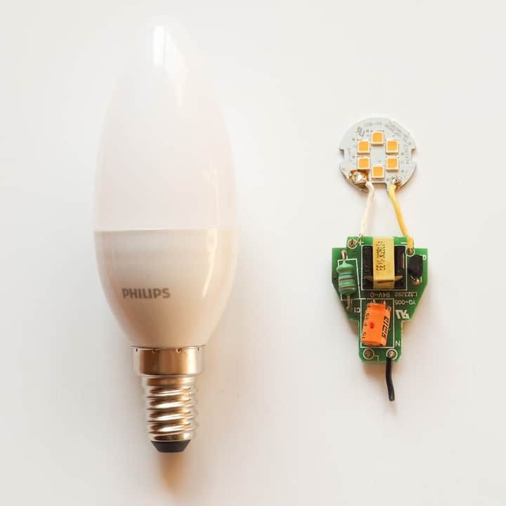 A Philips LED bulb next to its circuit board and components.