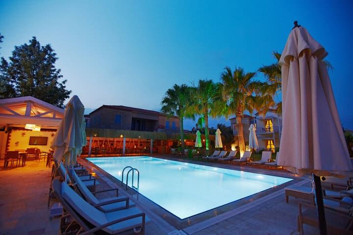 A tranquil poolside scene with palm trees and patio furniture at dusk.