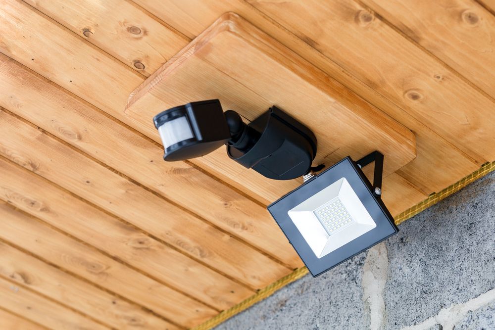 Black LED spotlight attached to wooden ceiling with motion detector