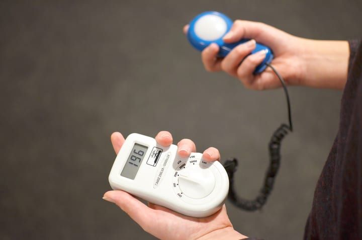 Person holding a light meter and a color temperature meter in both hands.