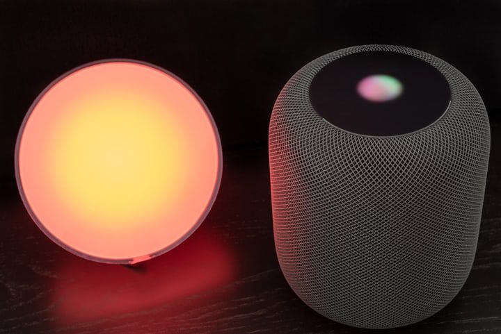 A glowing round LED lamp beside a speaker with glowing interface.