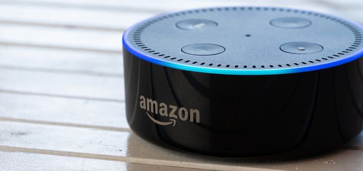 A black circular smart speaker with an illuminated edge and buttons on top.