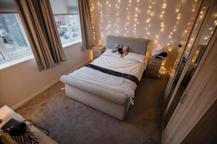 Cozy bedroom with a bed, fairy lights, and soft furnishings.