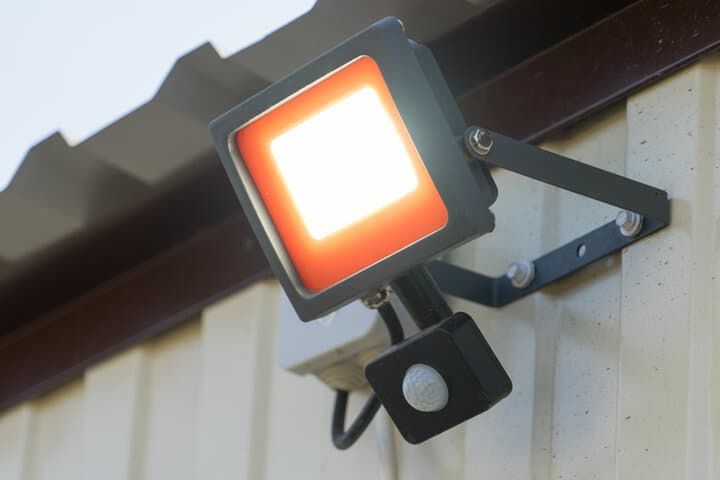 A square LED floodlight mounted on a wall with a motion sensor.