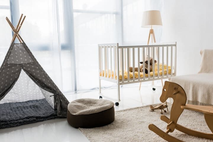 Brightly lit nursery featuring a crib, play tent, and rocking horse.