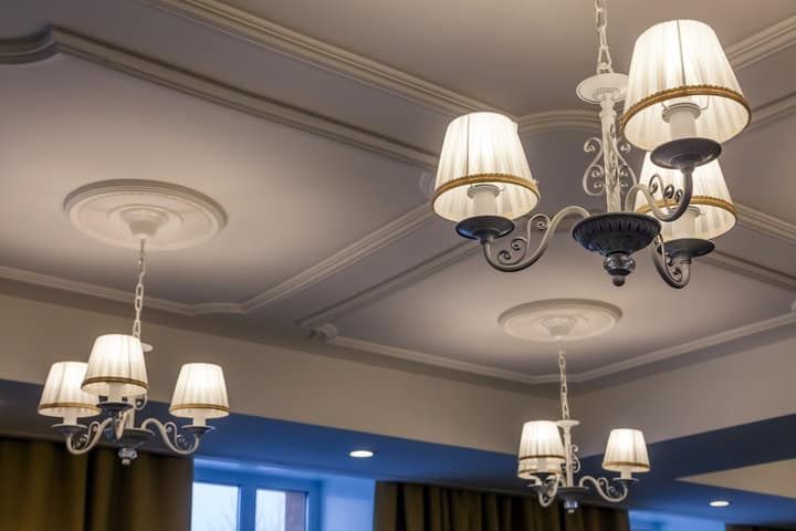 Chandeliers with fabric shades hanging from a decorative ceiling.