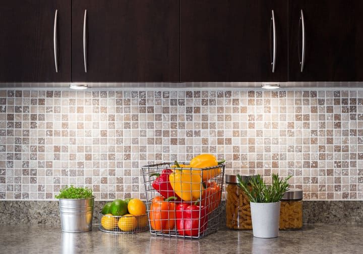 A kitchen countertop with fresh fruits, vegetables, and LED lighting above.