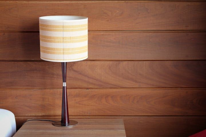 A stylish table lamp with a striped shade on a wooden table.