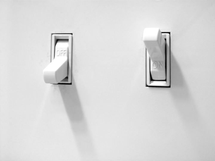 Two white light switches on a wall, one labeled OFF and the other ON.