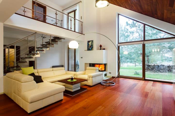 Modern living room with a light-colored sofa, large windows, and a spiral staircase.