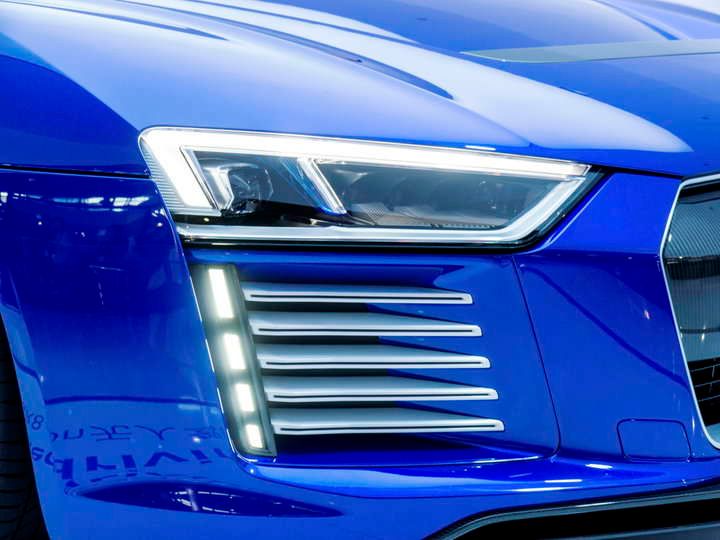 Close-up of a blue car's LED headlights and design features.