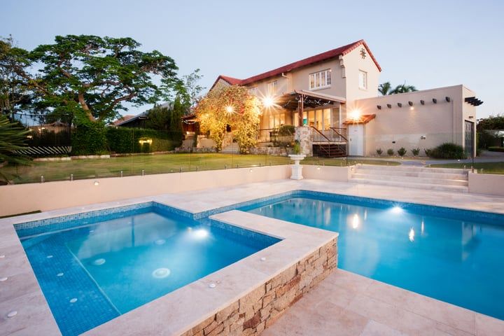 A modern house with landscaped garden and pool, illuminated by soft LED lights.