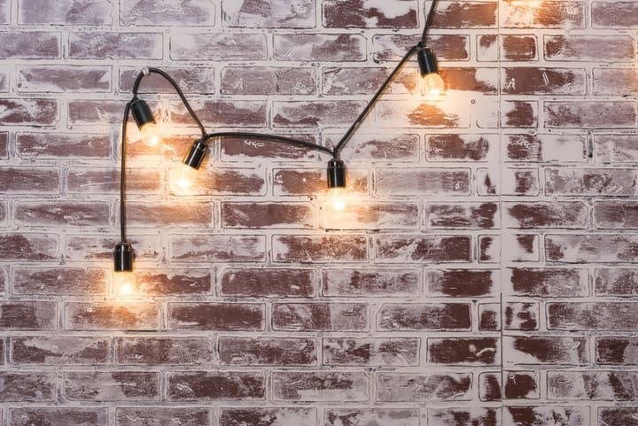 String lights hanging against a brick wall, illuminating the space warmly.