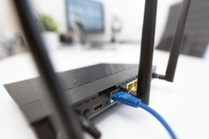 Close-up of a black router with Ethernet cables connected, showing ports.
