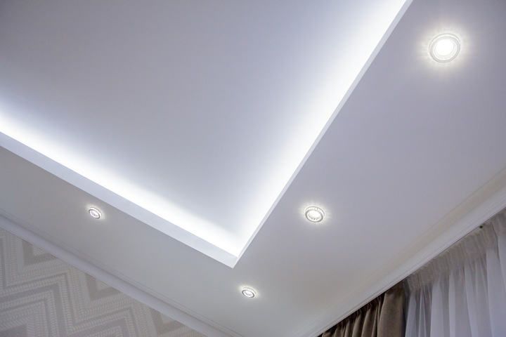 Modern ceiling with recessed LED lights illuminating a bright, white surface.