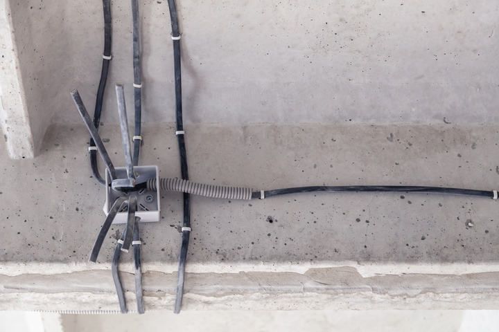 Ceiling view showing various electrical cables and connections on concrete.