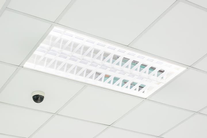 Ceiling-mounted LED light fixture with a security camera in view.