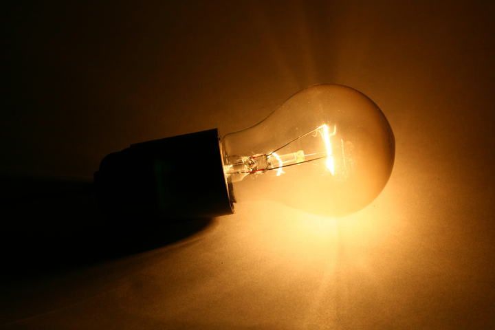 A glowing LED light bulb emitting a warm orange glow in a dark setting.