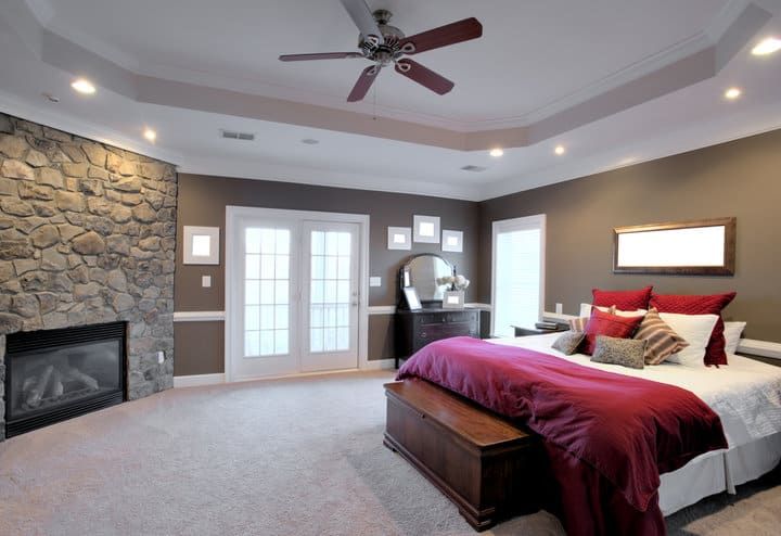 Cozy bedroom with stone wall, large windows, and stylish bedding.