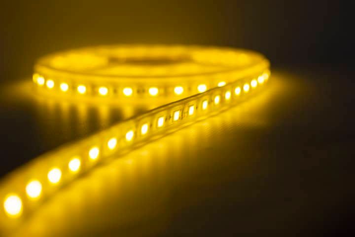 Flexible LED light strip with bright yellow illumination on a dark surface.
