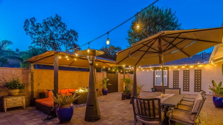 Cozy outdoor patio with lights, umbrellas, and seating in twilight.