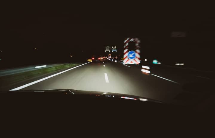 View of a dimly lit road at night with colorful traffic signs.